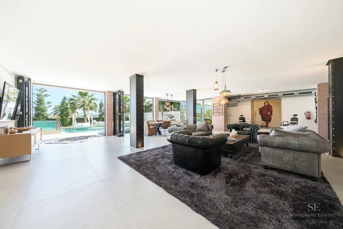 Aerial view of modern villa featuring a bright blue pool, lush garden, and minimalist architecture. Expansive terraces and abundant natural light.