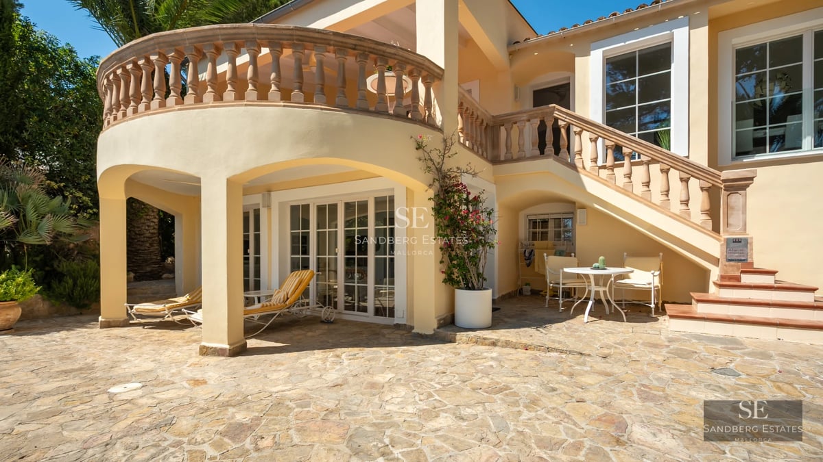 Exterior of a modern villa featuring an infinity pool, lush garden, and expansive terraces with panoramic sea views.