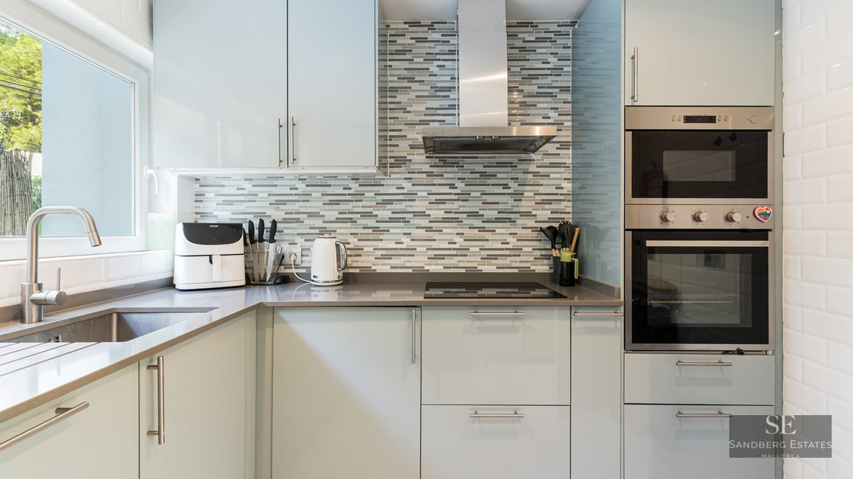 Cuisine moderne avec des armoires bleu clair, des plans de travail gris et une crédence en mosaïque.