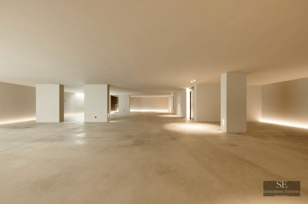 Large minimalist interior space with polished concrete floors, white pillars, and indirect LED floor lighting.
