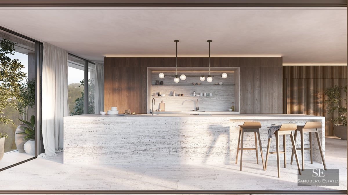 A large travertine kitchen island with wooden stools in a modern open-plan space with floor-to-ceiling windows.