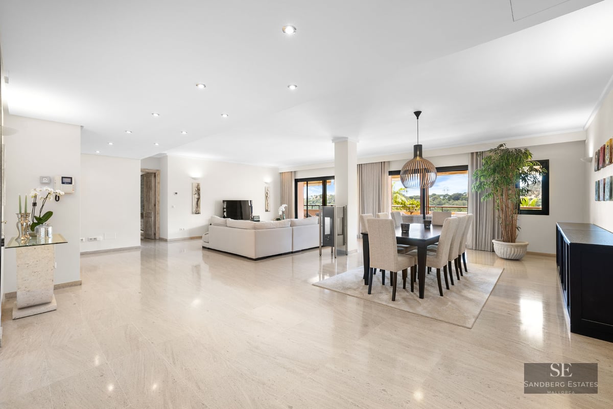 Intérieur lumineux à aire ouverte avec sols en marbre poli, un grand canapé blanc et une salle à manger moderne.