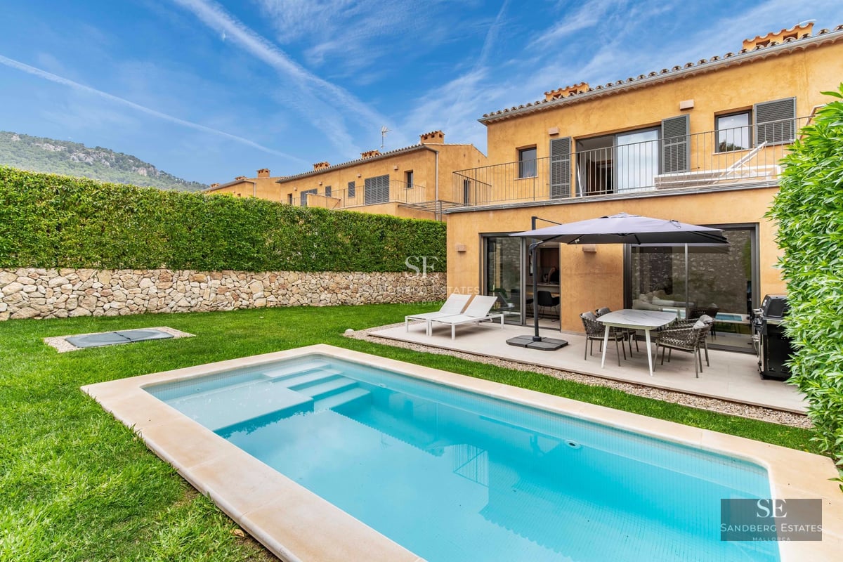 Exterior view of a modern villa with a pool, manicured garden, and expansive windows offering natural light.