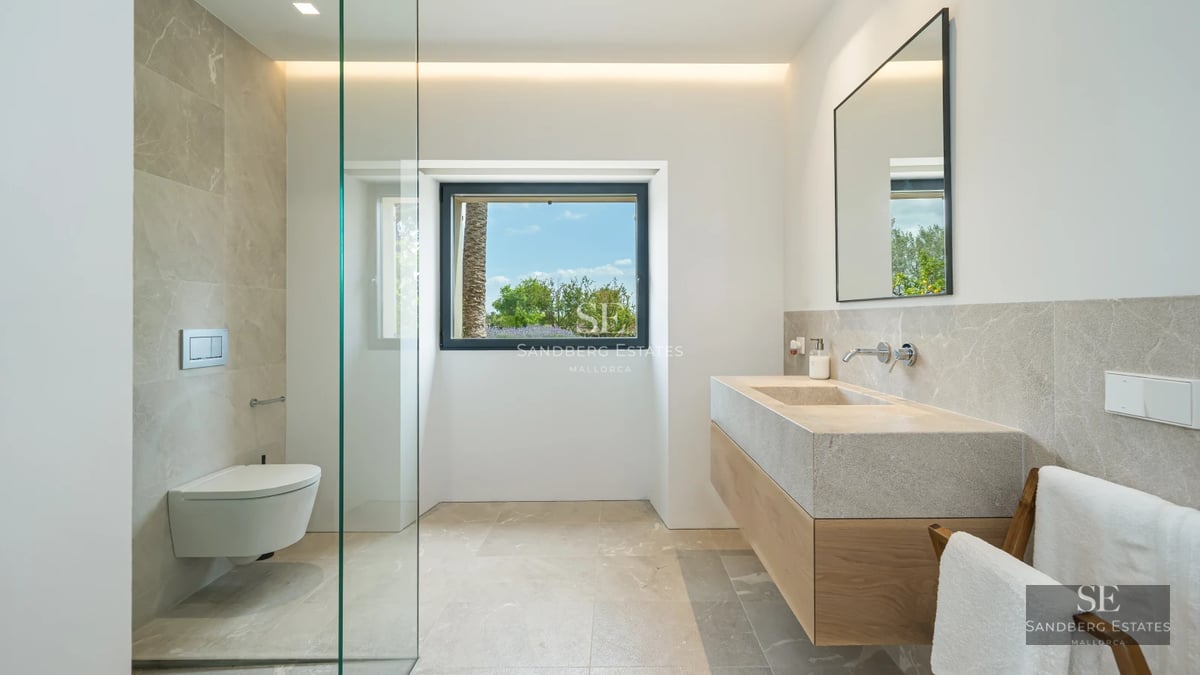 Bright living room with sea view windows. Modern design with white sofas, wooden coffee table and light tile floors.