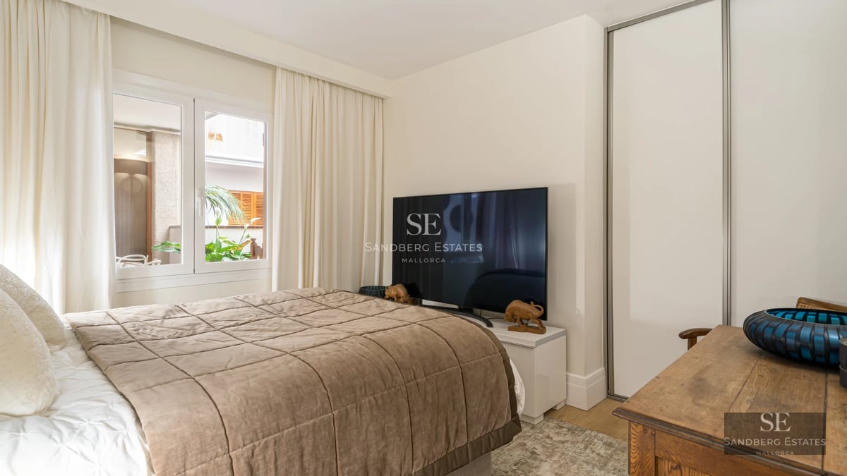 Modern living room with large windows, balcony with views, designer sofa, fireplace and light wood flooring.