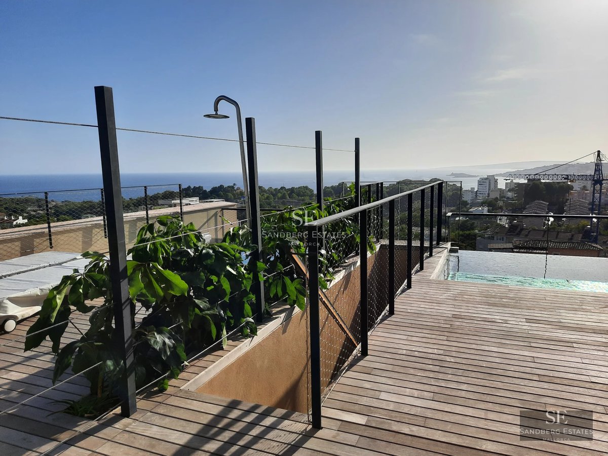 Spacious balcony with panoramic sea views from a modern apartment. Glass railing, stylish outdoor furniture.