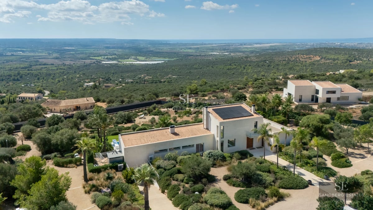 View of infinity pool and lush garden. Modern architecture with large windows and furnished terrace. Elegant and sophisticated design.