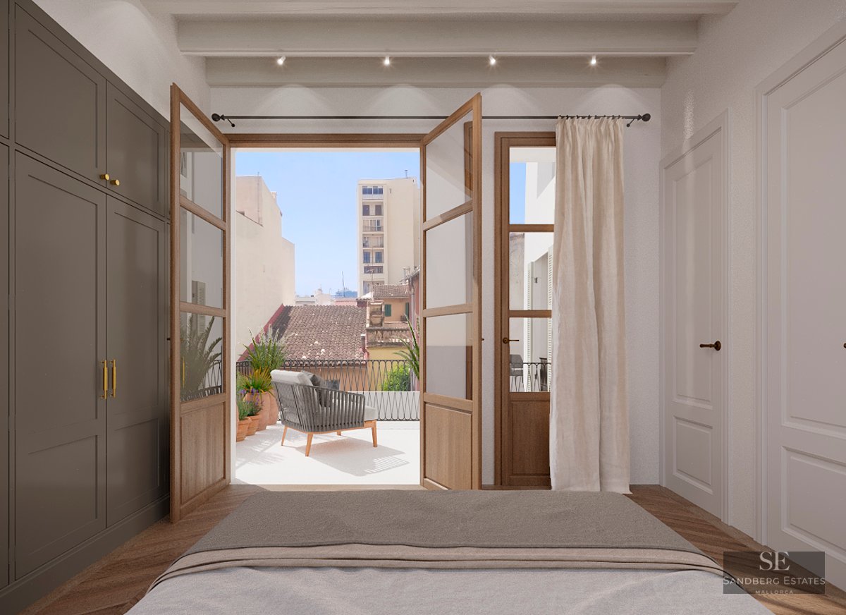 Modern bedroom view through open wooden doors to a sunny terrace with city views and outdoor seating.