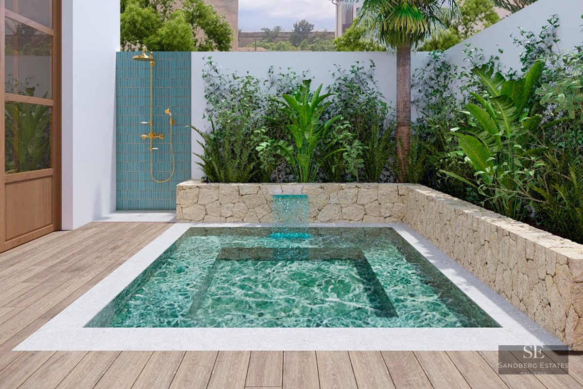Small turquoise pool with a waterfall, surrounded by stone walls and plants, next to a brass outdoor shower.