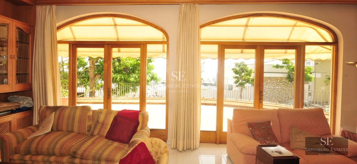 Spacious, bright living room featuring large windows, light wood floors, and minimalist decor offering panoramic sea views.