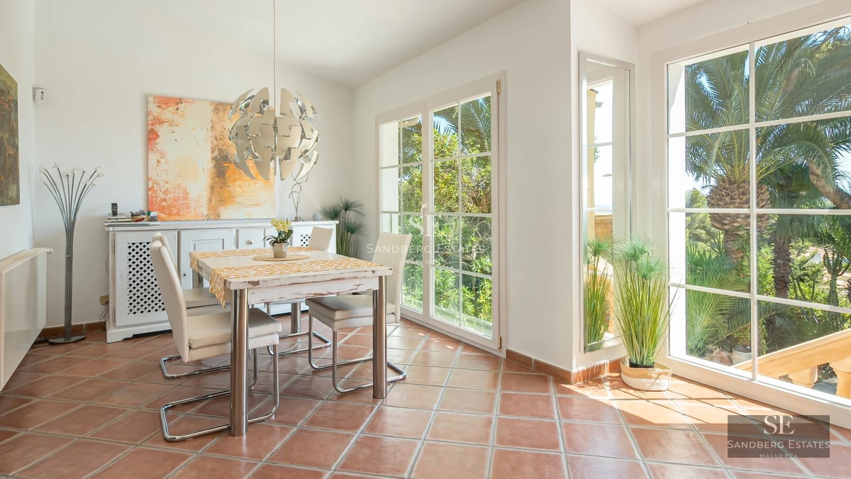 Bright living room with panoramic windows, modern sofas, and access to a balcony overlooking the Mediterranean Sea. Elegant and minimalist design.