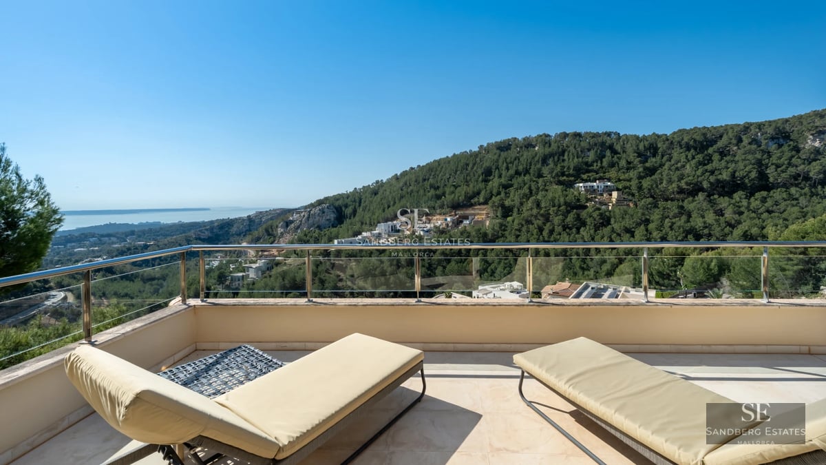 Modern living room with large windows, sea view, and designer furniture. Beige sofa, wood coffee table, and minimalist decoration.
