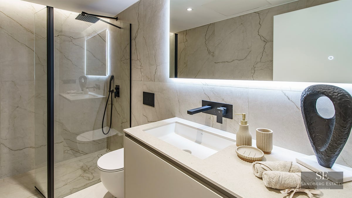 Contemporary bathroom featuring a glass walk-in shower, black fixtures, marble-effect tiles, and a backlit mirror.