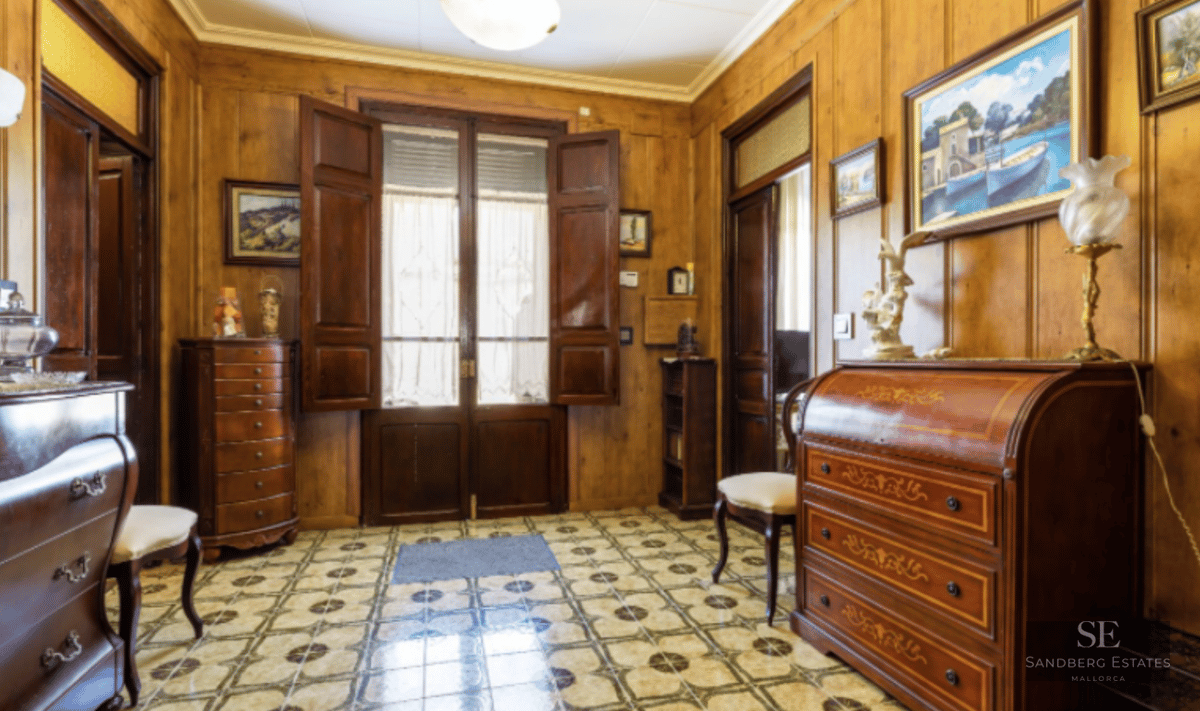 Entrance hall featuring warm wood-paneled walls, decorative patterned tile flooring, and classic antique furniture.