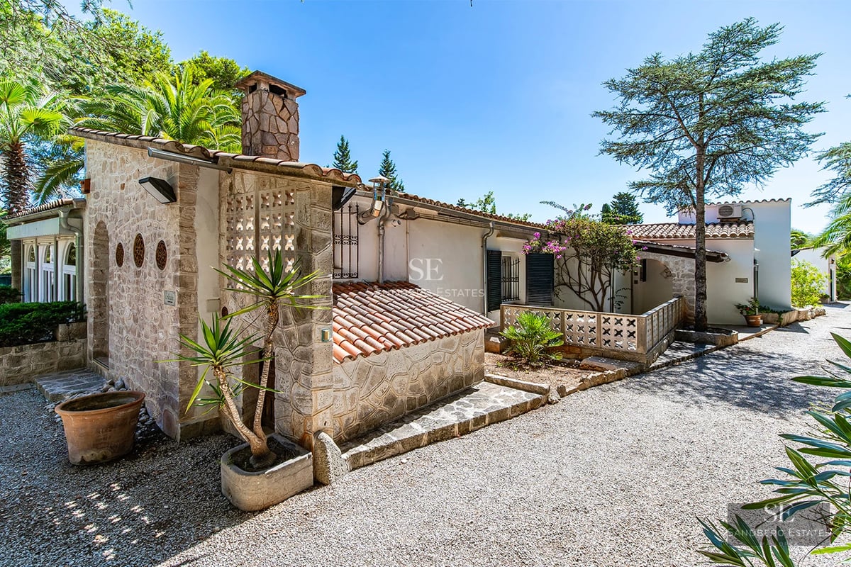 Exterior view of a modern villa with infinity pool, manicured garden, and expansive terraces. Minimalist architecture with large windows.