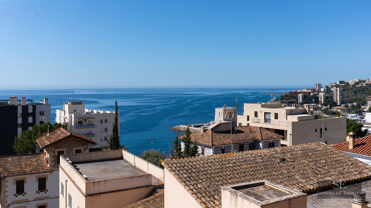 Panoramic view of the blue Mediterranean sea over coastal rooftops under a clear sky.