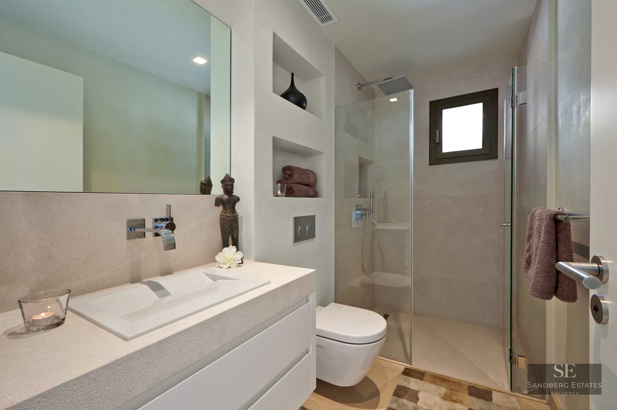 Modern bathroom featuring a stone vanity, wall-mounted toilet, and glass walk-in rain shower.
