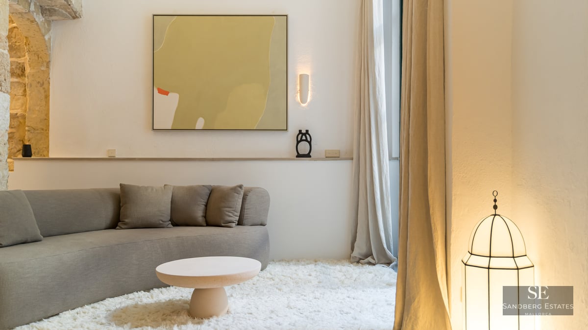 Salon minimaliste avec canapé incurvé gris, tapis shaggy blanc et arches en pierre naturelle.