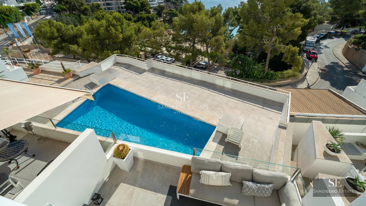 Luxurious living room featuring large windows, showcasing the outdoor pool. Modern design, natural lighting, and high-quality finishes.