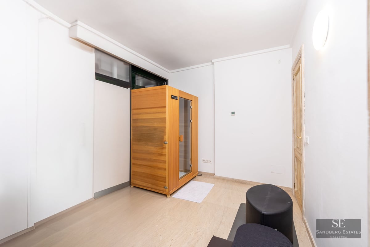 Pièce moderne blanche comprenant une cabine de sauna en bois autoportante et un sol en pierre claire.