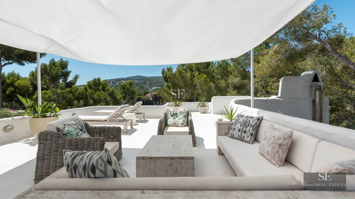 View of infinity pool and garden of a modern villa with lounge chairs and outdoor living area. Minimalist architecture and lush landscaping.