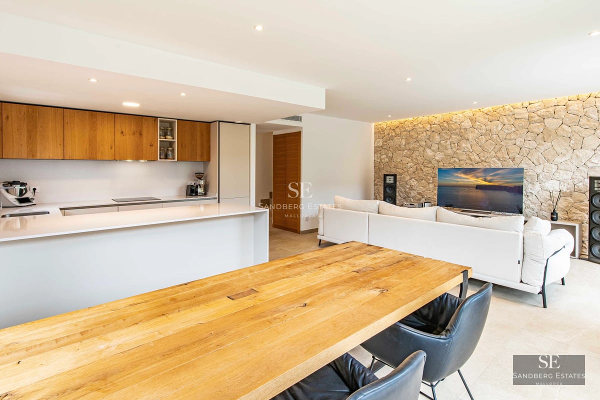 Bright living room with large windows, beige sofa, modern fireplace, and panoramic views. Minimalist and elegant design.