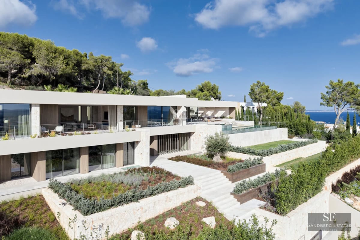 View of garden with infinity pool, sun loungers, and lush vegetation. Modern and relaxing design.