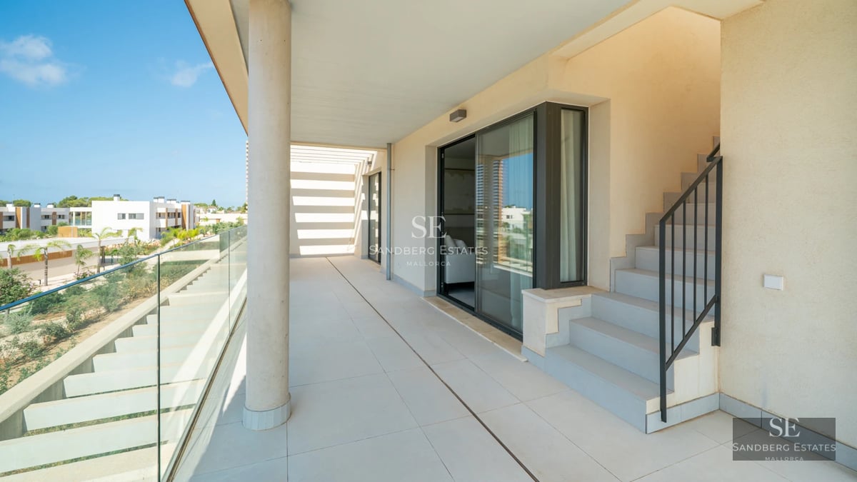 Spacious balcony with sea view. Modern outdoor furniture, glass railing, and tiled floor. Contemporary design.