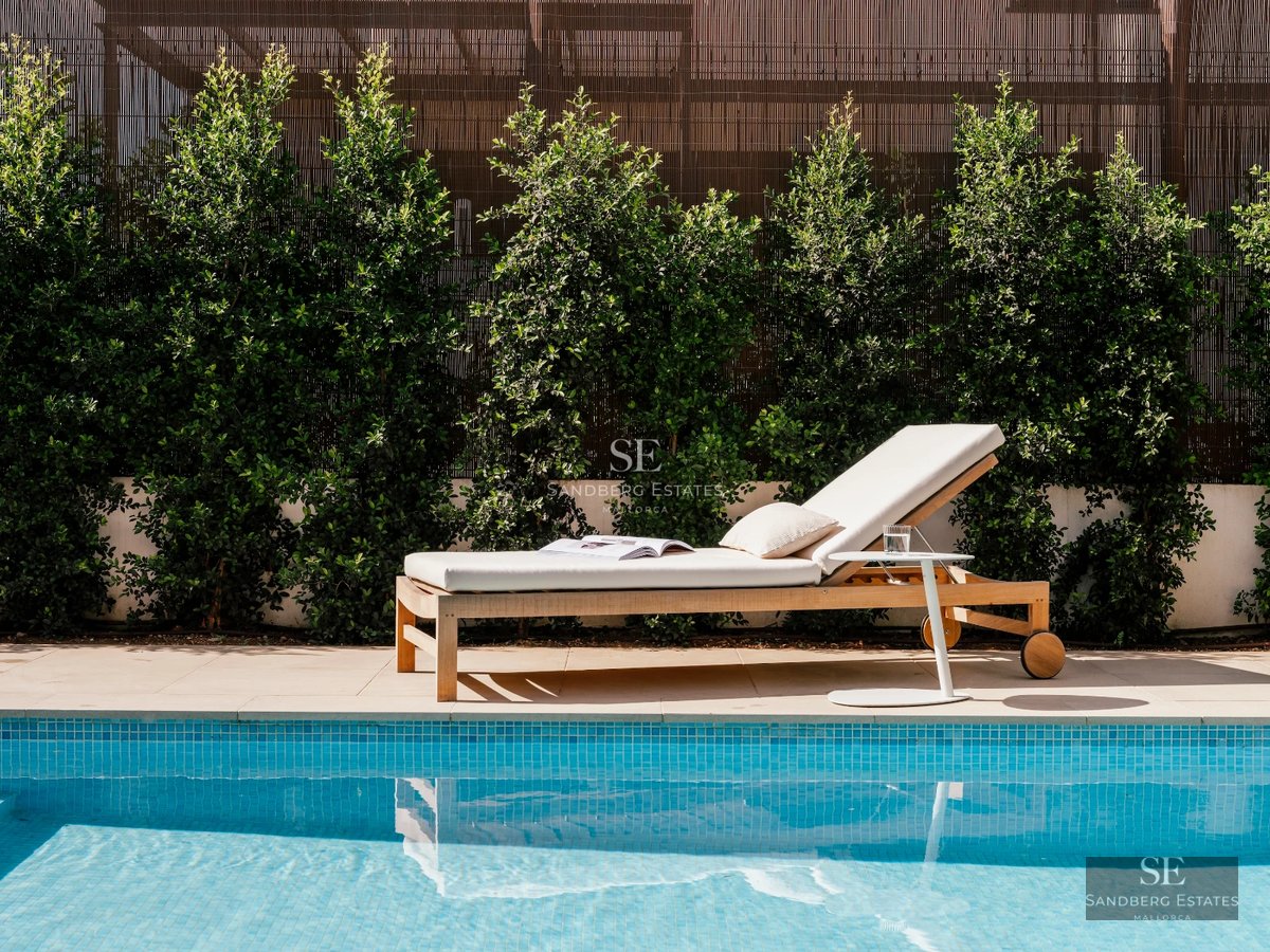 Spacious living room featuring large windows, elegant fireplace, modern furniture, and access to a balcony with a view. Natural lighting and design details.