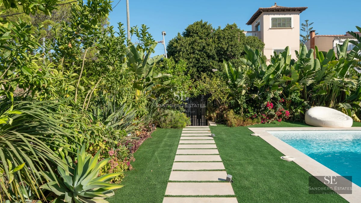 Expansive living room with panoramic windows, reflecting pool, and lush garden. Modern design and high-quality finishes. Natural light.