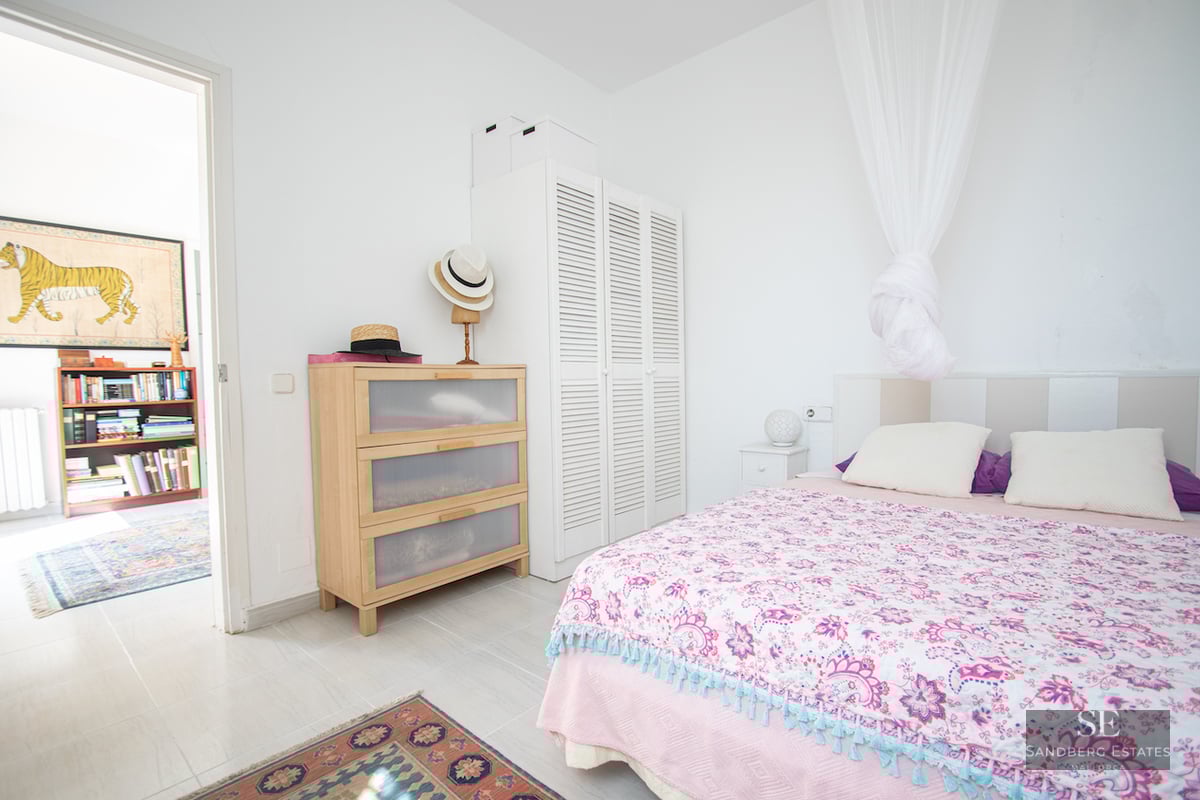 Bedroom with pink patterned bedspread, white canopy, light wood dresser, and white louvered wardrobe on tiled floor.