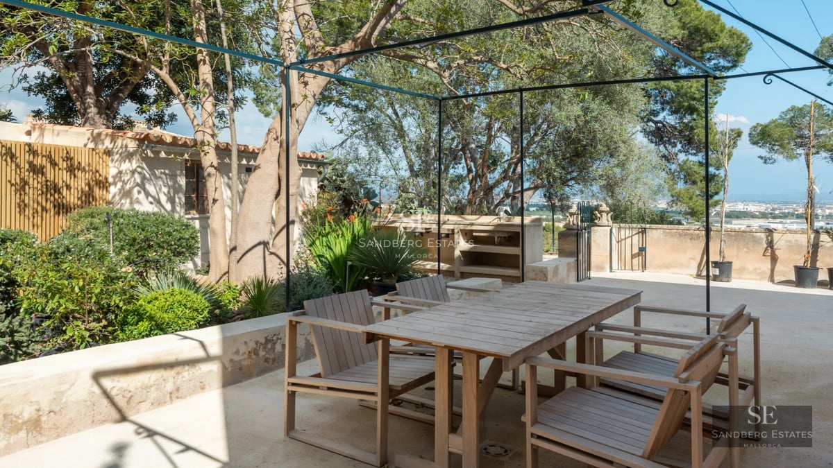 View of a modern swimming pool with sun loungers, surrounded by lush greenery. Minimalist facade of the house in the background.
