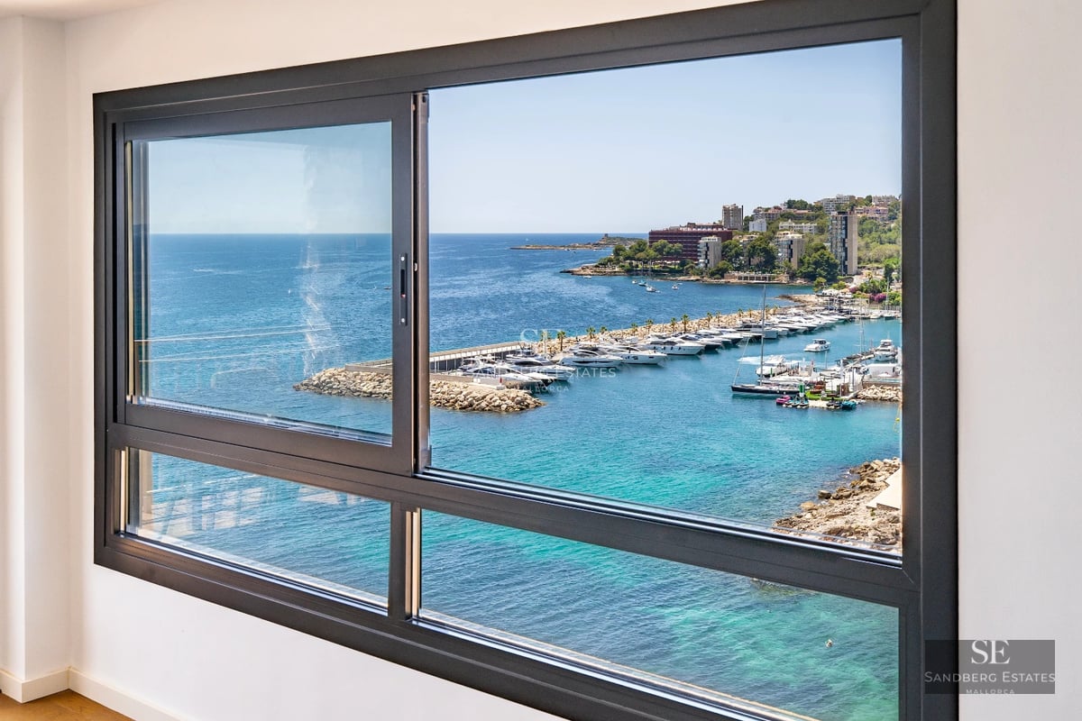 Spacious balcony with sea view. Modern design, glass railing, outdoor furniture. Natural and warm lighting.