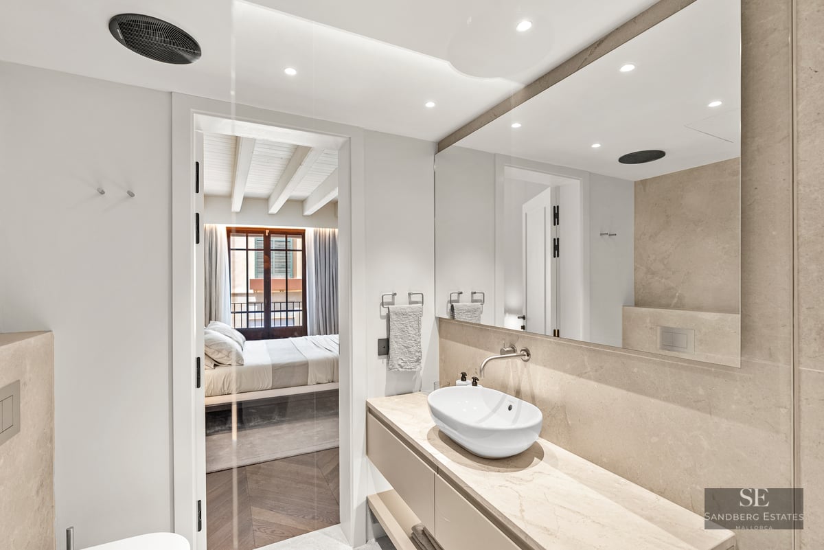 Luxury bathroom featuring a stone countertop, oval vessel sink, and a view into a bright bedroom.