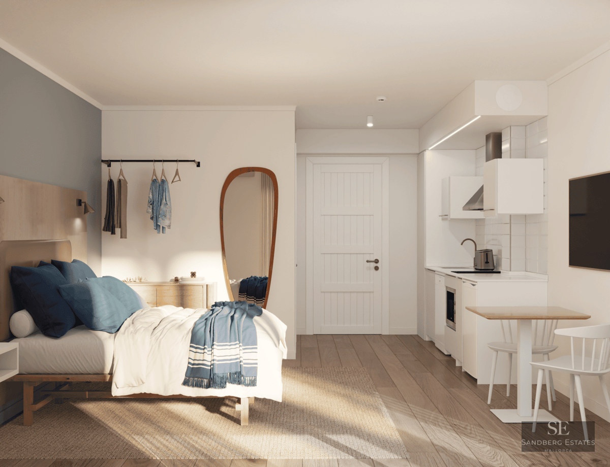 Studio lumineux avec lit aux accents bleus, grand miroir et kitchenette blanche moderne.