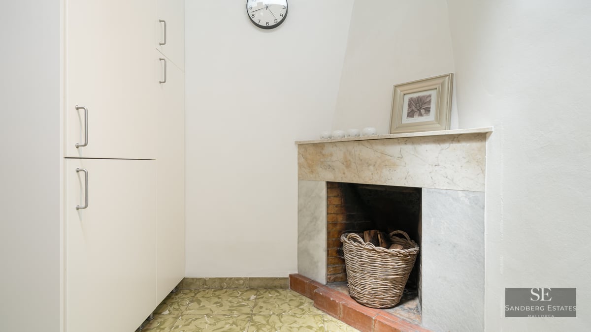 Interior corner featuring a marble fireplace, a wicker wood basket, and a tall white storage cabinet.