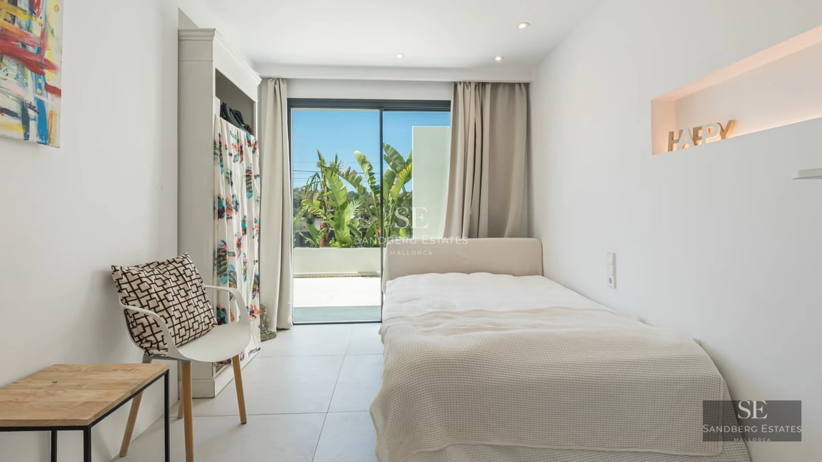 View of infinity pool with armchairs, lush vegetation, and modern architecture with large windows.