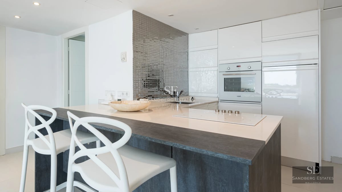 Spacious balcony with panoramic sea view. Glass railing, wooden floor, and modern outdoor furniture. Natural light.