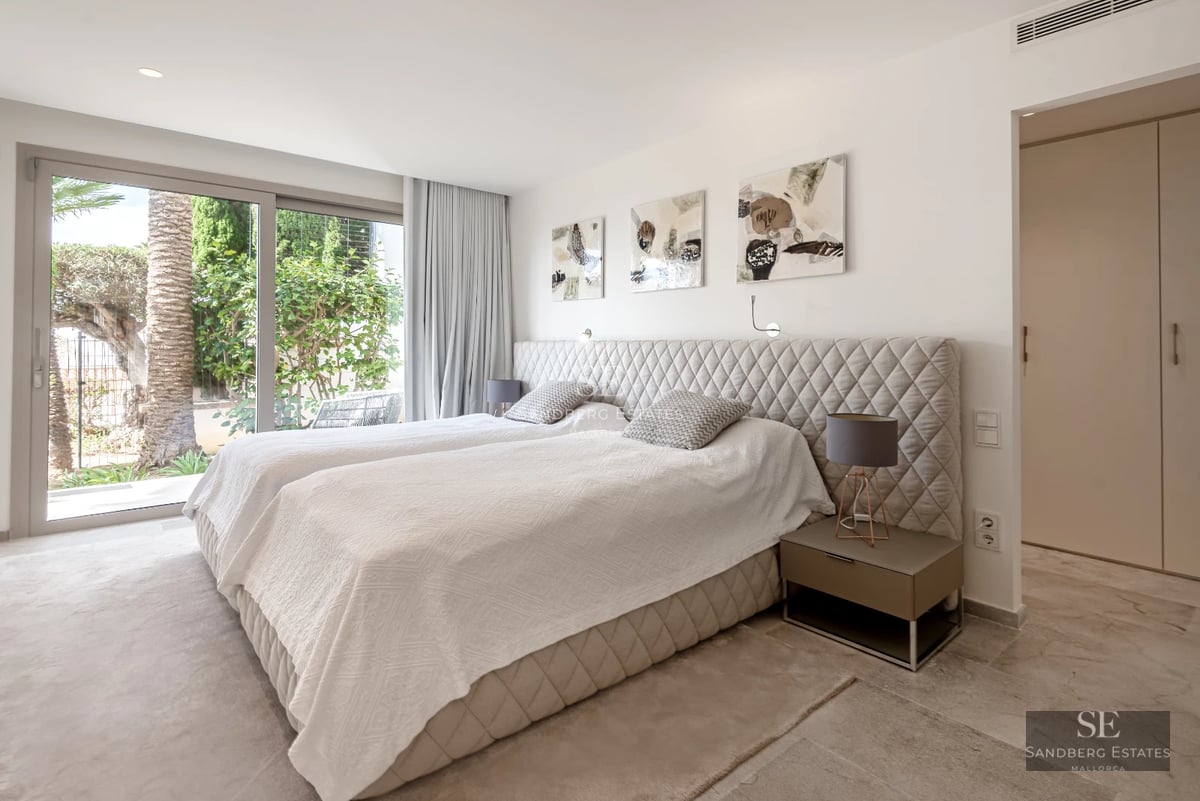 View of a luxurious villa featuring a pool, sun loungers, and lush greenery. Modern architecture with large windows.