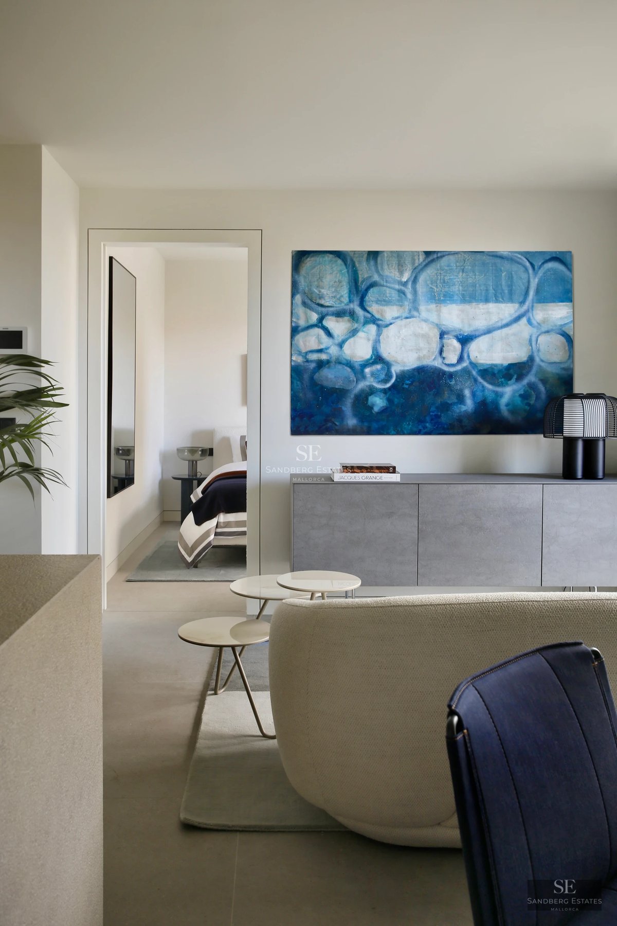 Bright interior with large windows, light wood floors, modern designer furniture, and minimalist decor. City view.