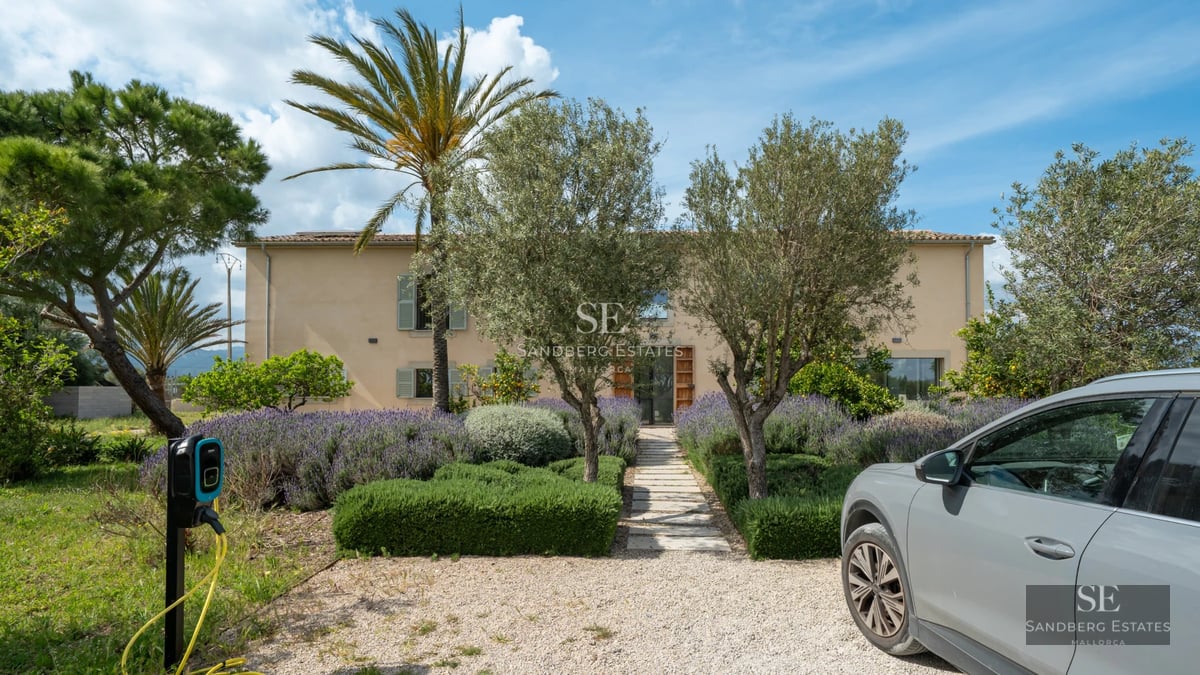 Balcony view with swimming pool. Modern furniture, glass railing, blue sky. Visible vegetation. Luxury and comfort.