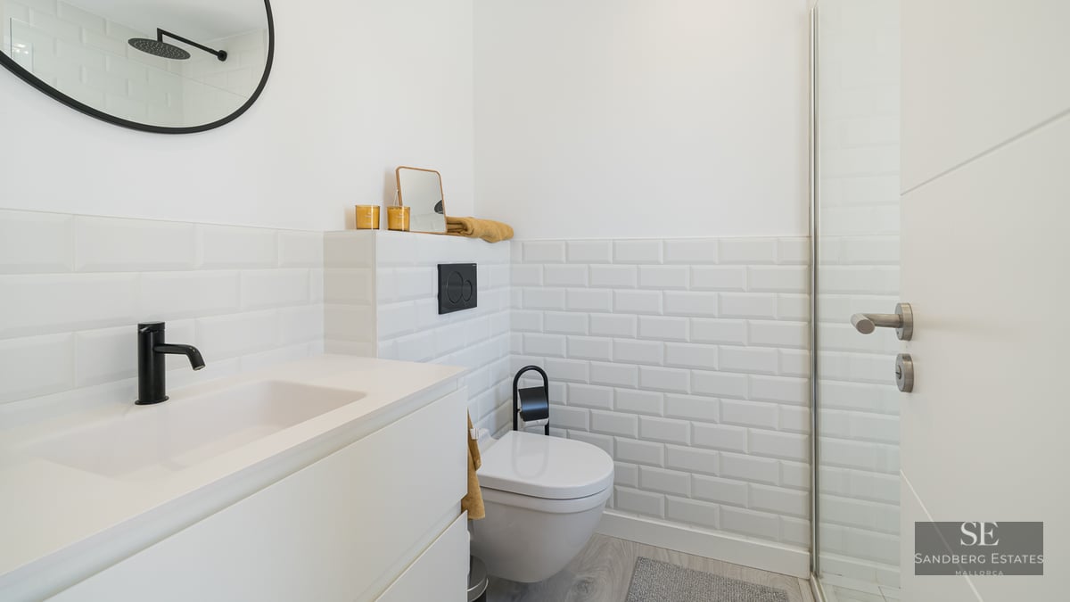 Modern white bathroom featuring subway tiles, black fixtures, and a sleek minimalist vanity.