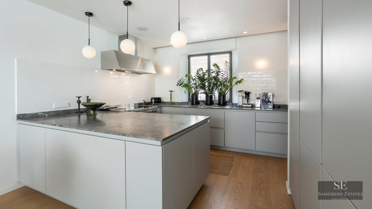 Contemporary kitchen featuring a large gray marble island, minimalist gray cabinetry, and white globe pendant lights.