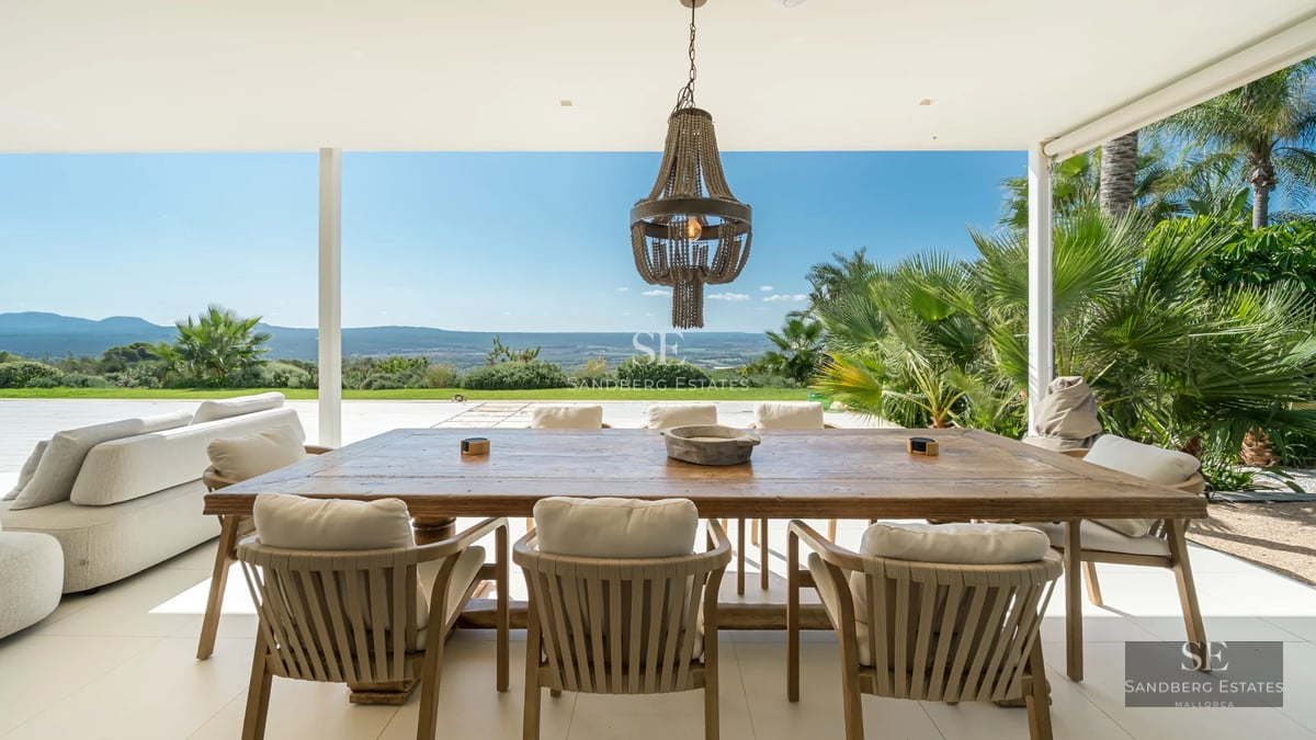 View of a modern pool surrounded by lush greenery and a house with large windows. Minimalist design.