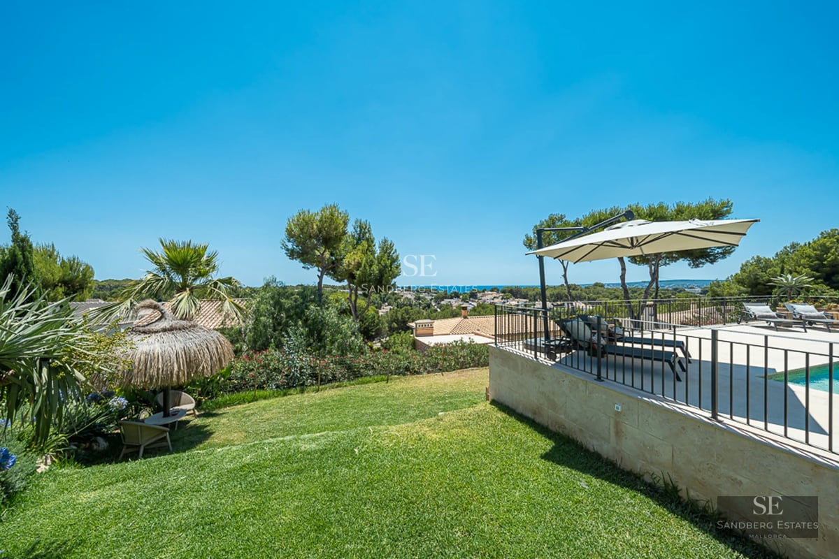 Salon spacieux avec grandes baies vitrées et balcon avec vue sur la mer. Intérieur moderne avec canapés design et lumière naturelle abondante.