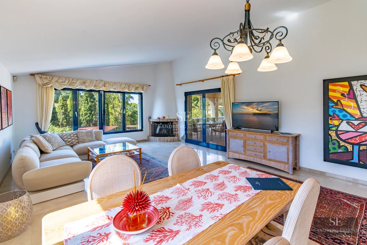 View of a luxurious house with an infinity pool, lush garden, and modern architecture with large windows.