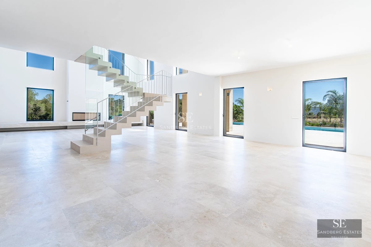 View of a modern villa with a pool. Large windows, minimalist design, blue pool, and well-maintained garden.