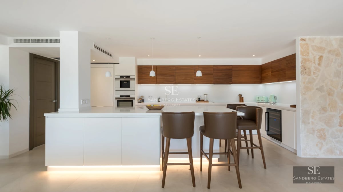 Exterior view of a modern villa with a pool, lush gardens, and expansive windows illuminating the interior.