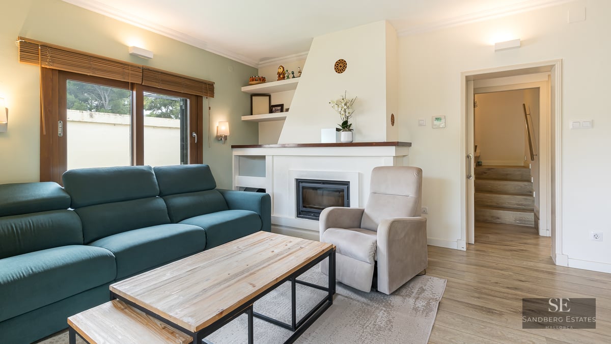 Modern living room with a teal sofa, white built-in fireplace, wooden coffee table, and beige armchair.