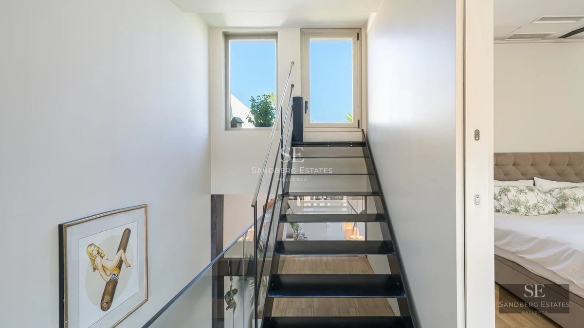 Spacious living room with panoramic windows, light wood floors, modern furniture, and abundant natural light. View of garden and pool.